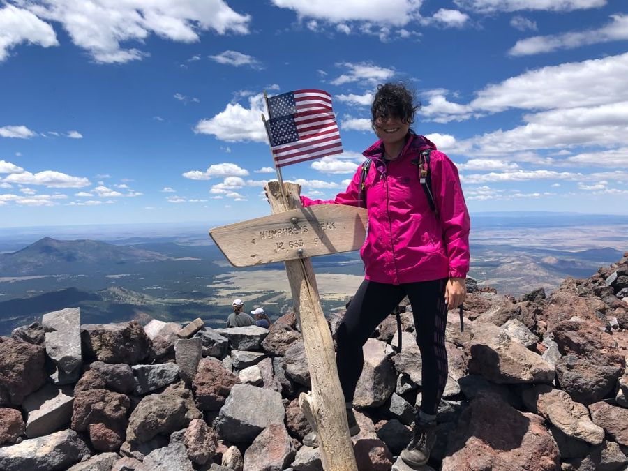 Sahar at the Humphreys Peak summit sign, 12,633 feet, with an American flag
