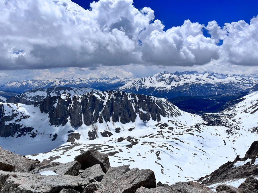 Snow-covered Sierra Nevada peaks under big clouds, seen from Mount Whitney